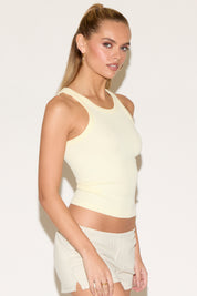 Model wearing a yellow tank top and beige shorts.