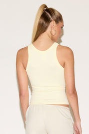 Model wearing a yellow tank top and beige shorts.