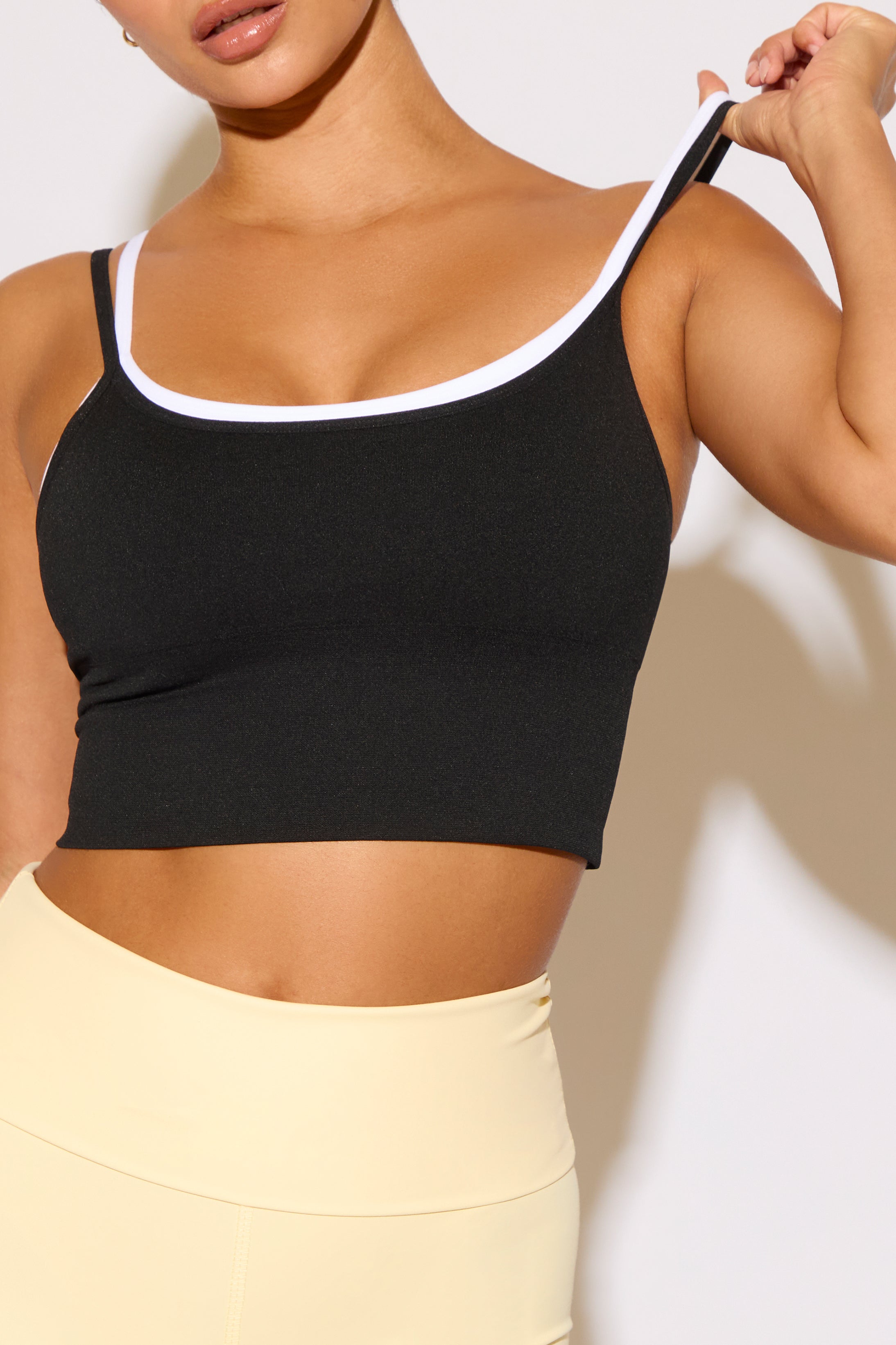 Person wearing a black sports bra with white trim against a neutral background