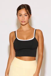 Woman wearing a black sports bra and yellow leggings against a white background