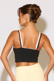 Woman wearing a black crop top with thin straps against a light background