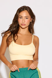 Woman wearing a yellow sports bra and green shorts with yellow stripes on a white background