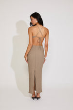 Woman wearing a beige dress with a backless design on a white background