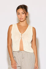 Woman wearing a cream-colored knit vest against a white background