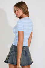 Woman wearing a light blue striped shirt and denim skirt on a white background