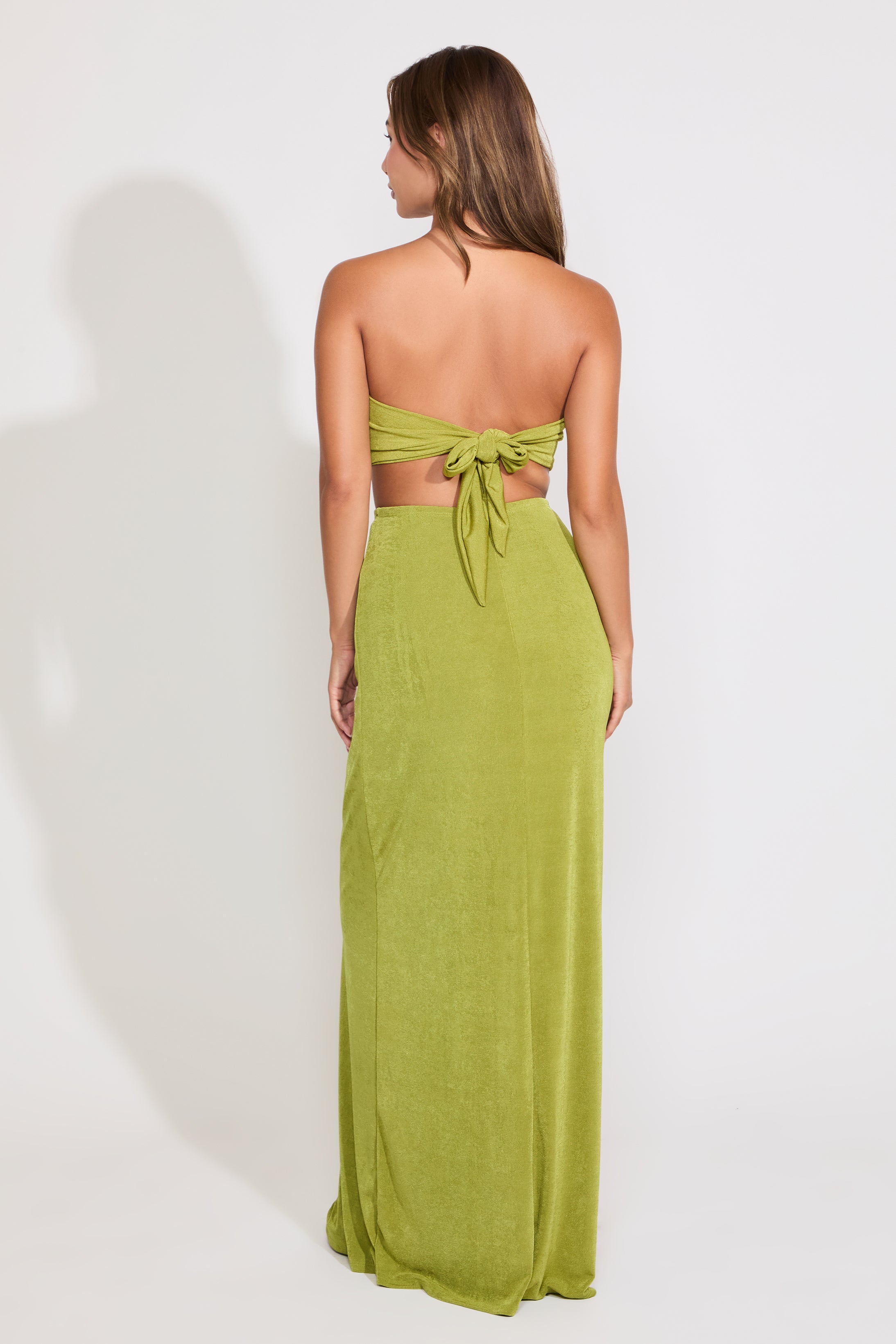 Model is wearing a green metal detail strapless cutout maxi dress on a white background.