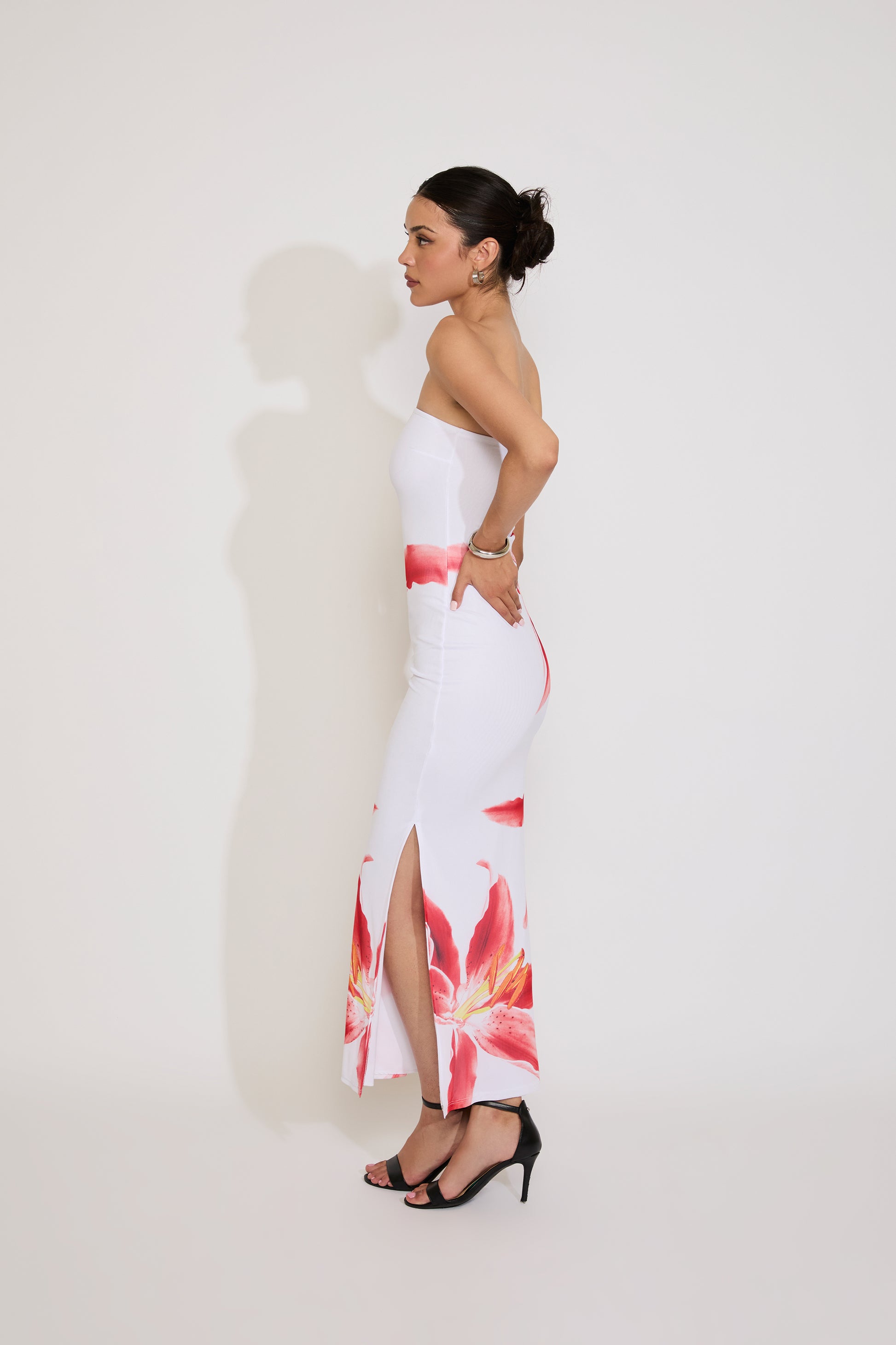 Woman wearing a white dress with floral patterns on a plain background