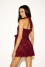 Woman wearing a burgundy lace dress against a white background