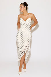 Woman wearing a white dress with black polka dots on a white background
