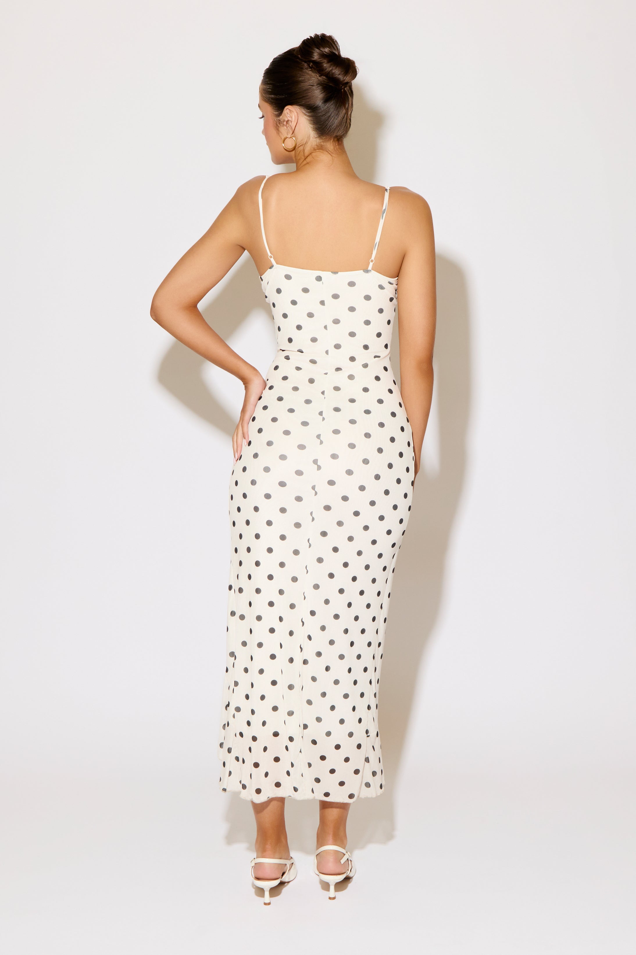 Woman wearing a white polka dot dress on a white background