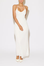 Woman wearing a white halter neck dress on a plain background