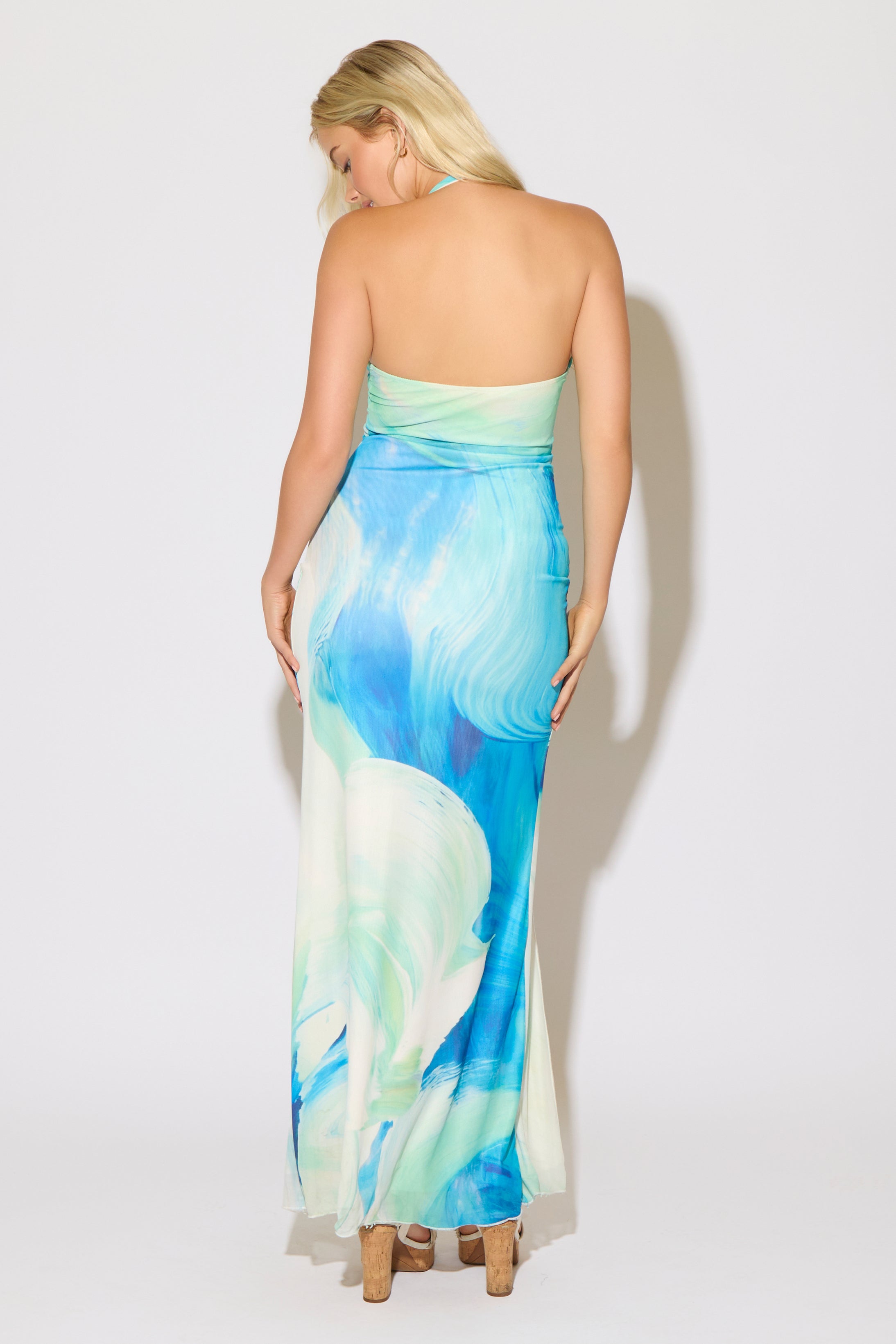 Model is wearing a blue abstract print with a high neck halter maxi dress on a white background.