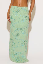Green floral skirt worn by a person on a white background