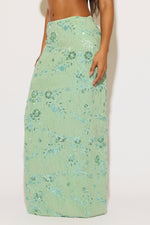 Green floral dress worn by a person on a white background