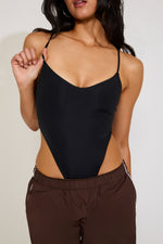 Person wearing a black swimsuit with cut-out design on a plain background