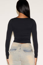 Person wearing a black long-sleeve top and light blue jeans on a white background