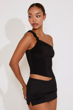 Woman wearing a black one-shoulder top and skirt set on a white background