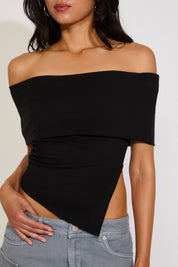 Black off-shoulder top worn by a person on a white background
