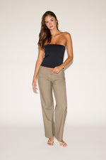 Woman wearing a black strapless top and beige pants on a white background