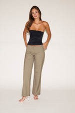 Woman wearing a black strapless top and beige pants on a white background