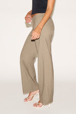 Person wearing beige wide-leg pants on a plain background