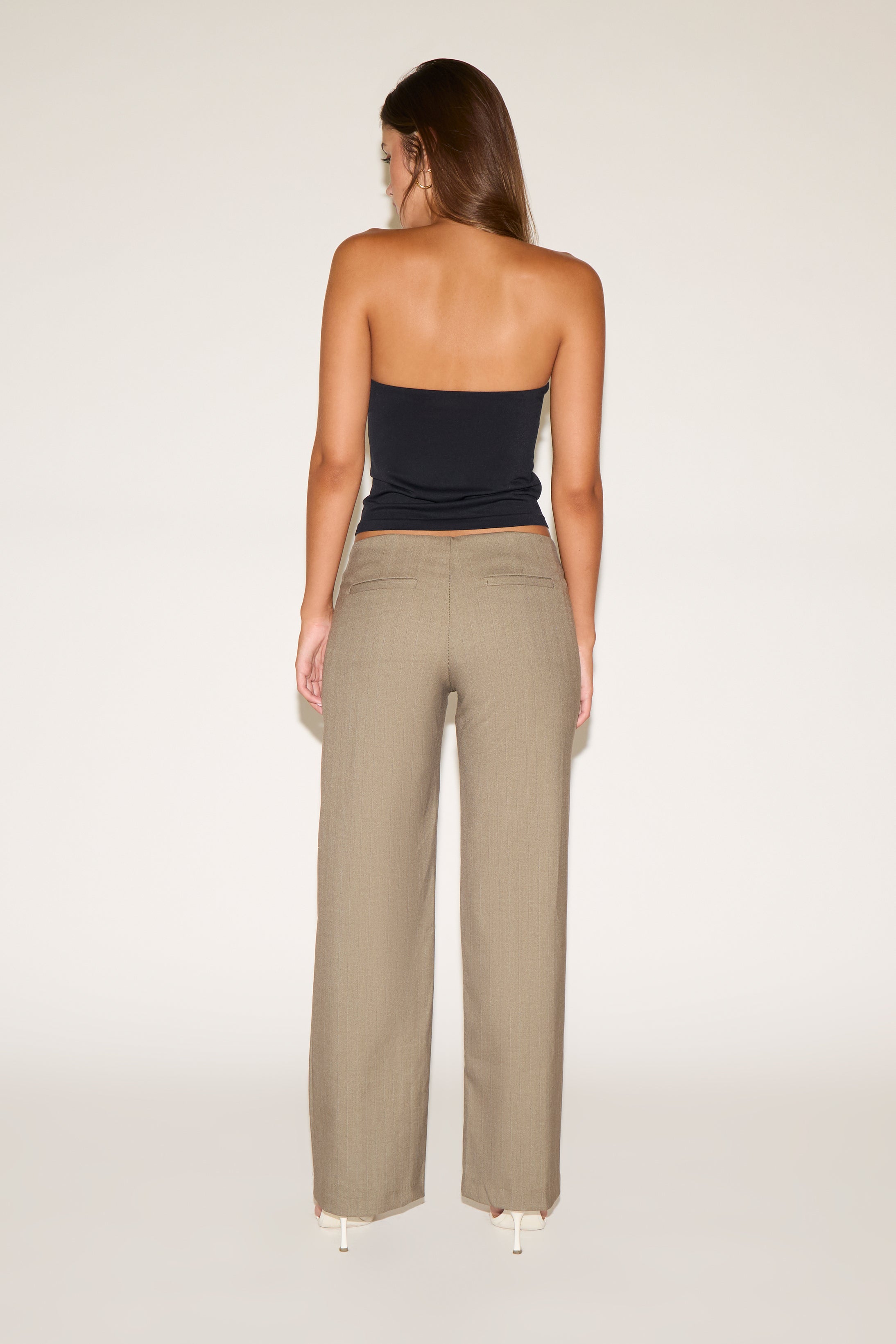Woman wearing a strapless top and beige pants on a white background