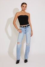 Woman wearing a black strapless top and light blue ripped jeans on a white background