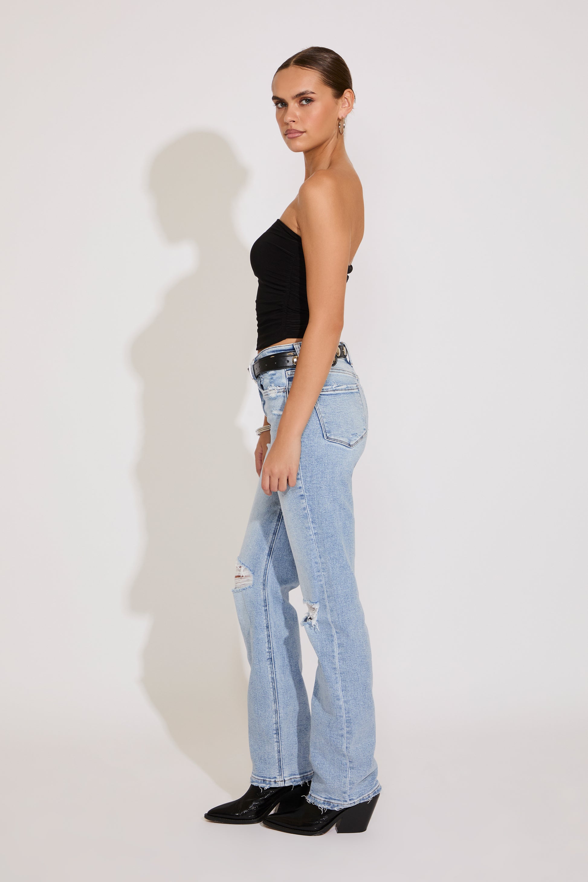 Woman wearing a black top and light blue jeans on a white background