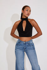 Woman wearing a black halter top and blue jeans against a white background