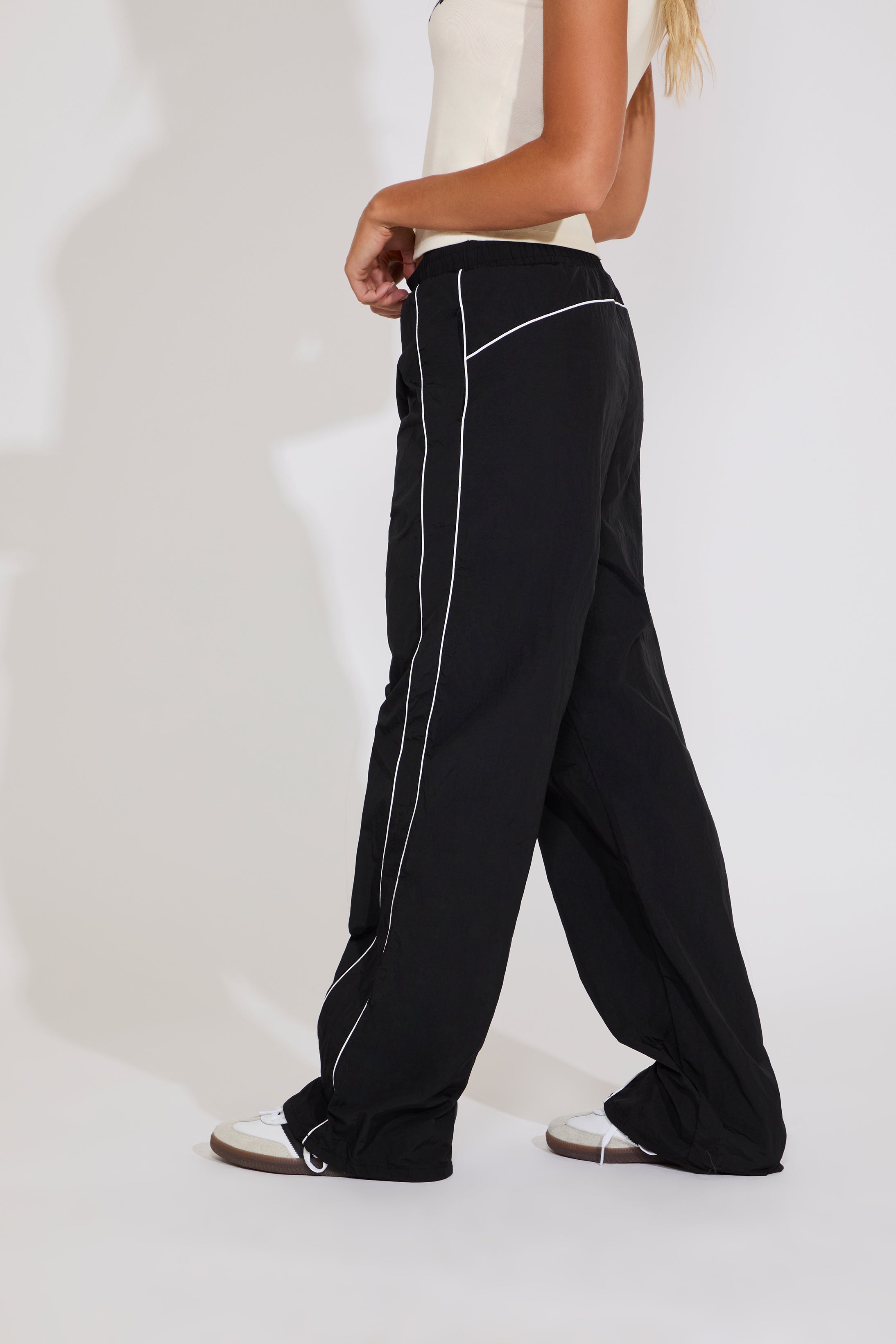 Black pants with white piping worn by a person on a white background