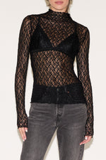 Black lace long-sleeve top worn by a person on a white background