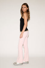 Woman wearing a black top and pink pants on a white background