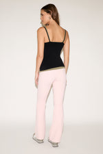 Woman wearing a black tank top and pink pants on a white background