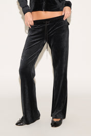 Black velvet pants worn by a person on a white background