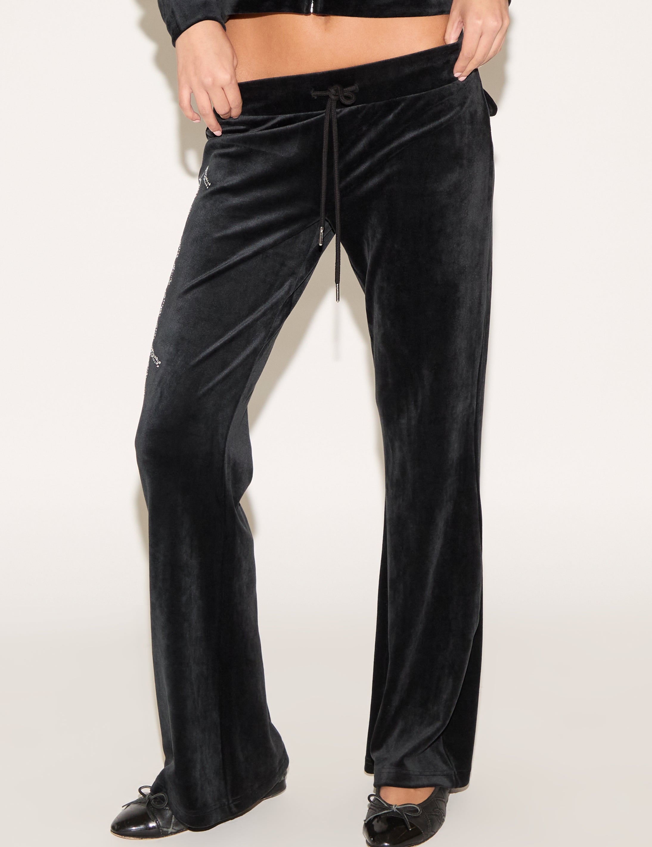 Black velvet pants worn by a person on a white background