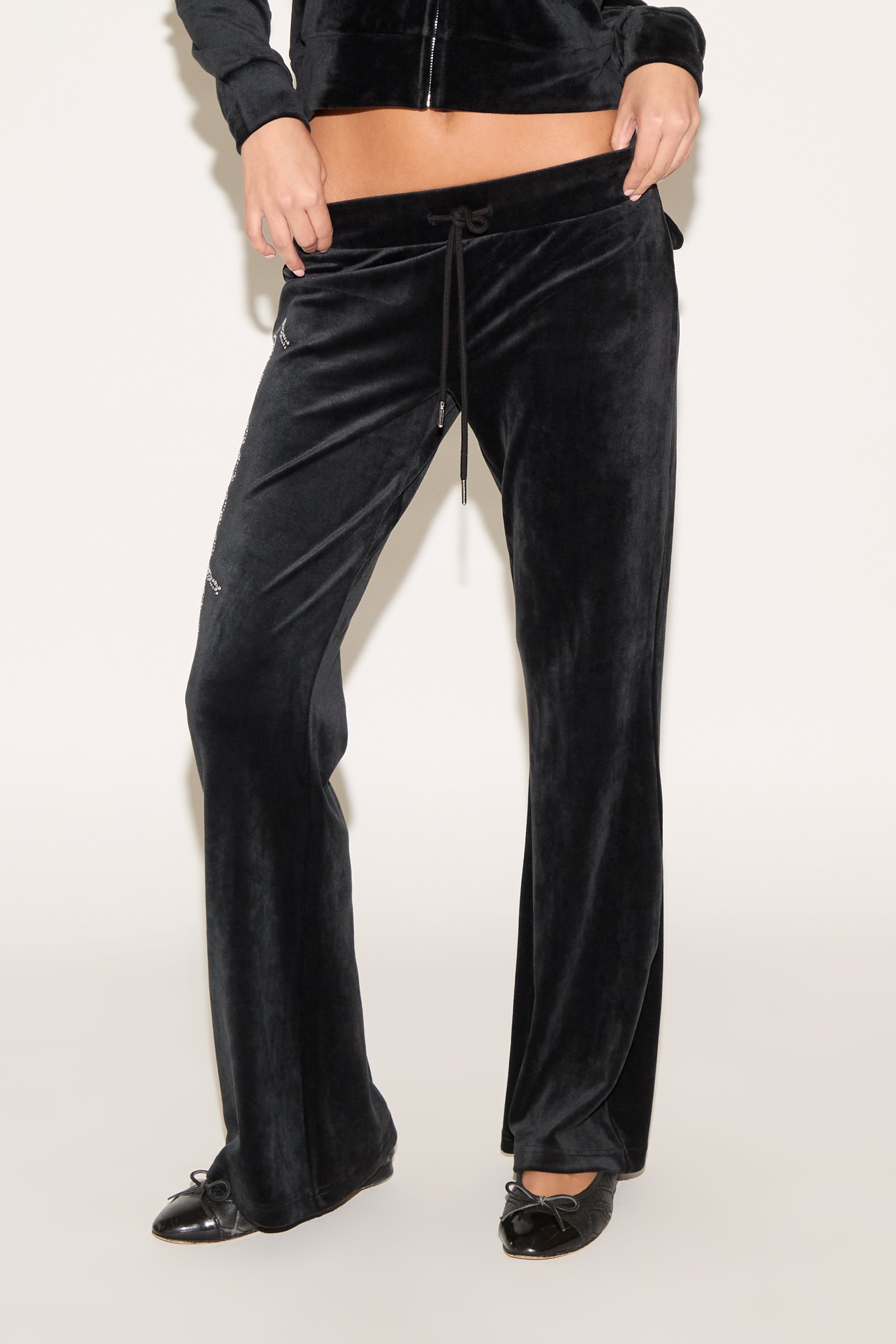 Black velvet pants worn by a person on a white background