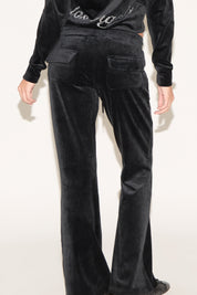 Black velvet pants worn by a person on a white background