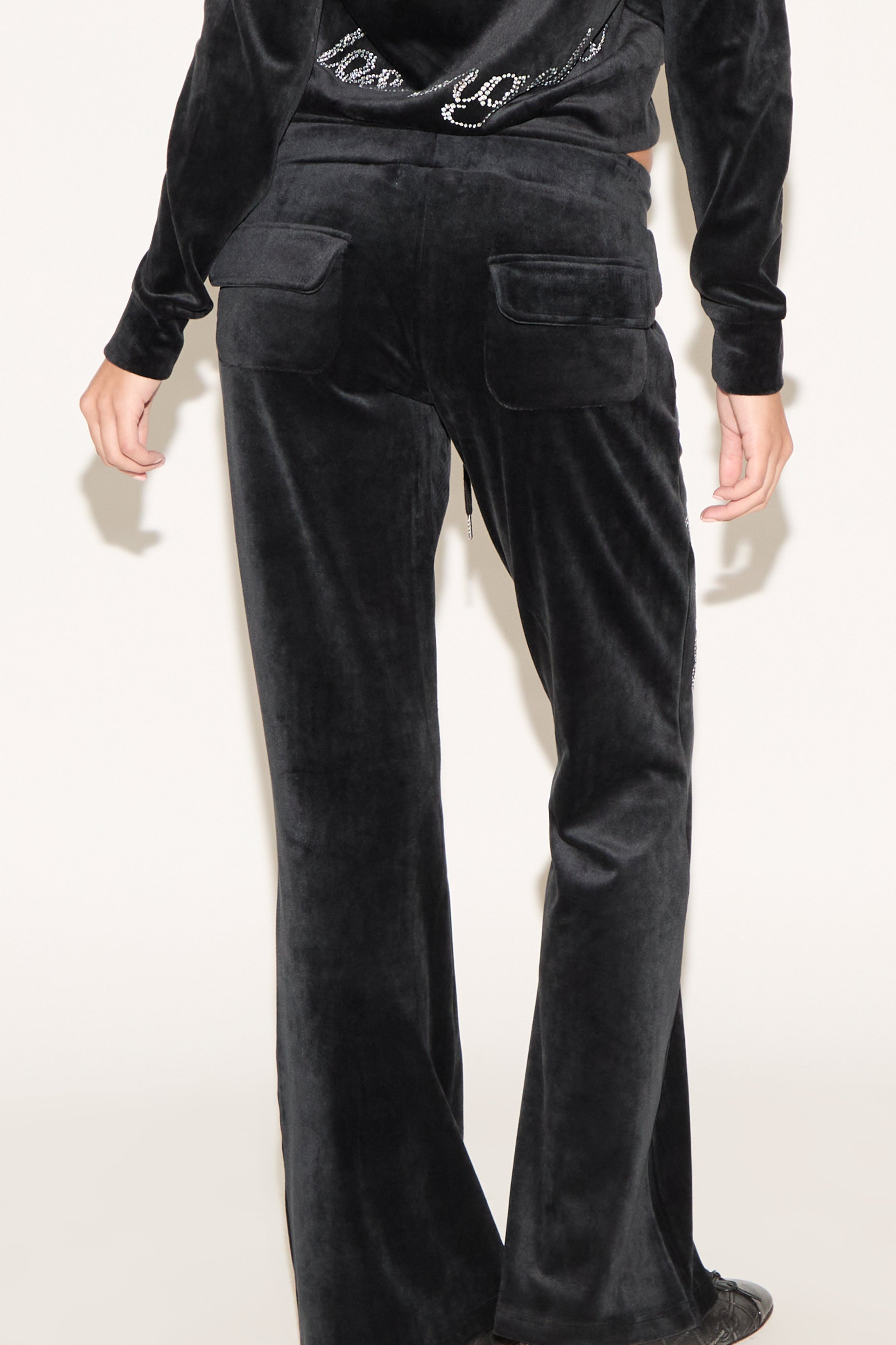 Black velvet pants worn by a person on a white background