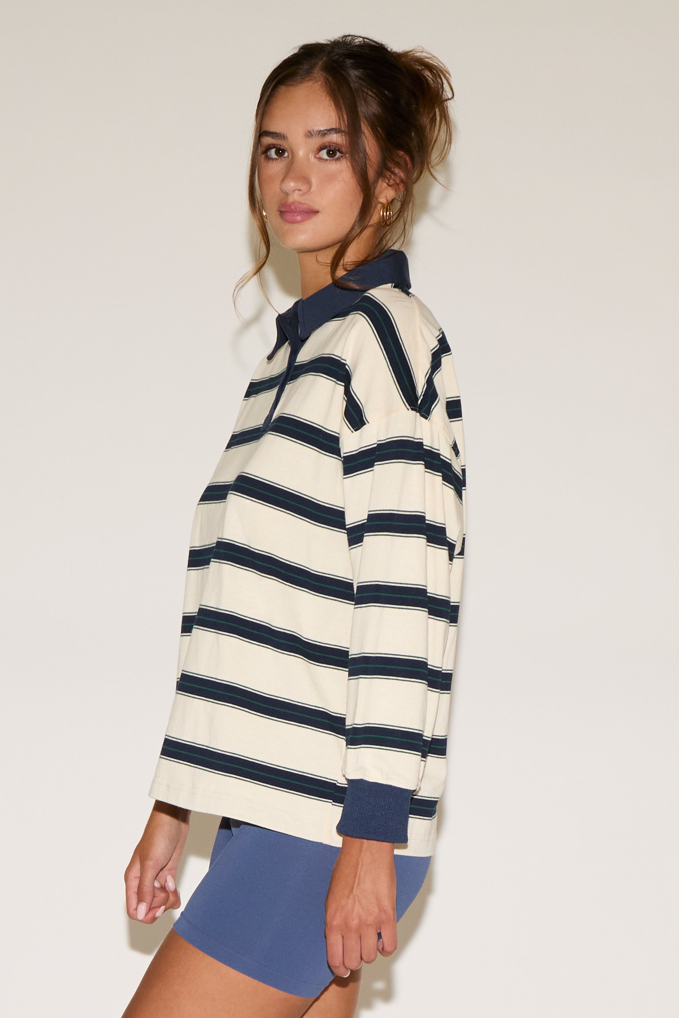Woman wearing a striped sweater and blue shorts against a plain background
