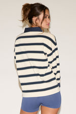 Woman wearing a striped sweater and blue shorts against a plain background