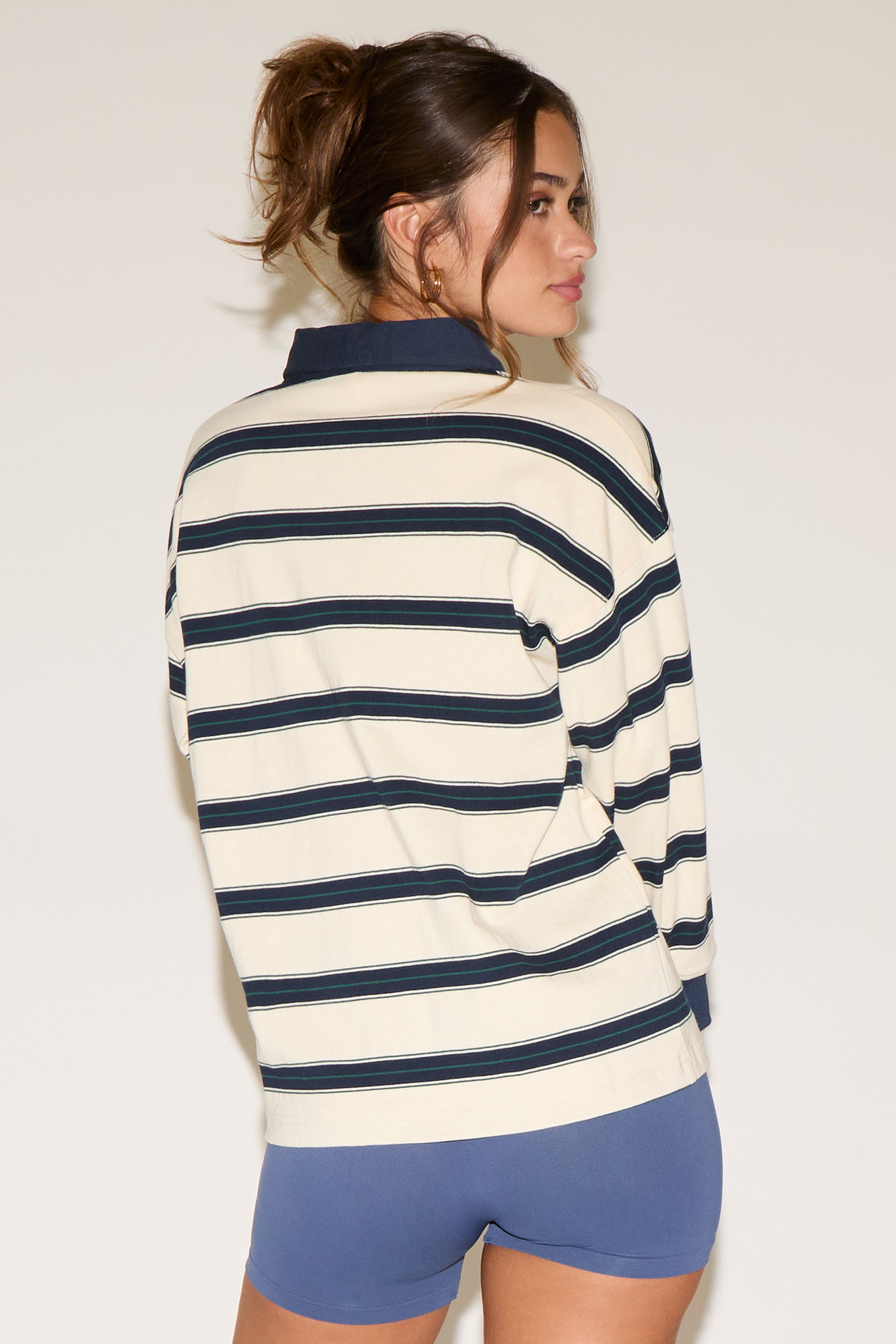 Woman wearing a striped sweater and blue shorts against a plain background