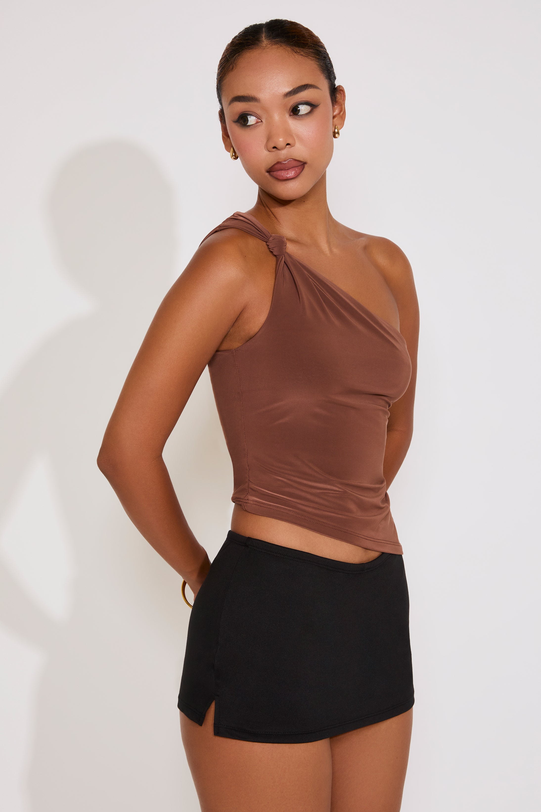 Woman wearing a brown halter top and black skirt on a white background