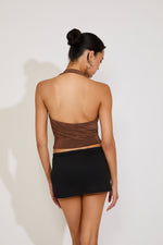 Woman wearing a brown halter top and black skirt against a white background