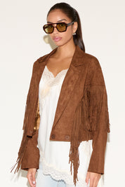 Woman wearing a brown suede jacket with fringe details on a white background