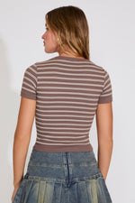 Woman wearing a brown and beige striped shirt with a plain background