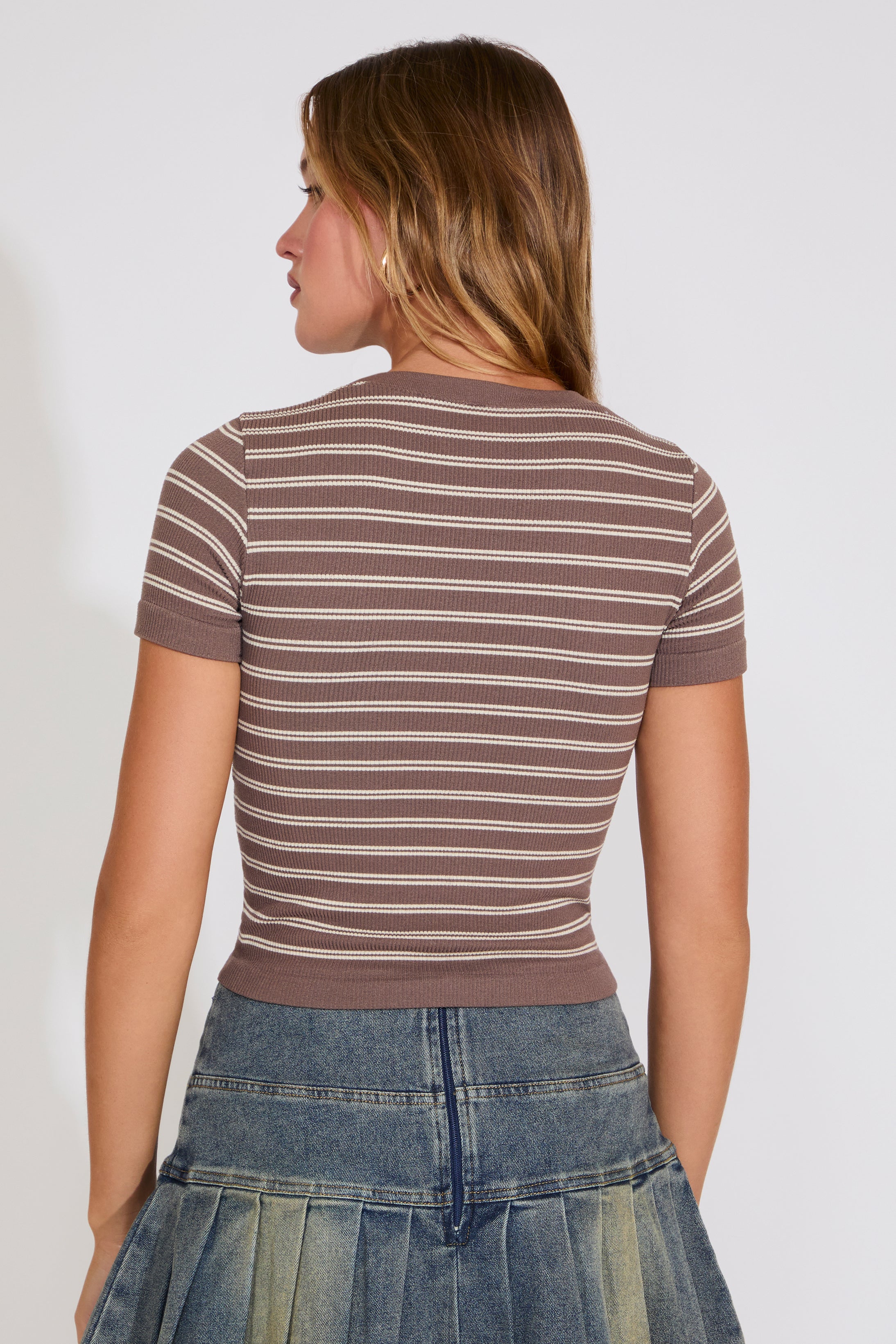 Woman wearing a brown and beige striped shirt with a plain background
