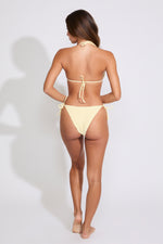 Model is wearing a solid yellow bikini set on a white background. 