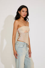 Woman wearing a strapless top and jeans against a plain background