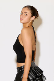 Woman wearing a black crop top and black skirt against a white background