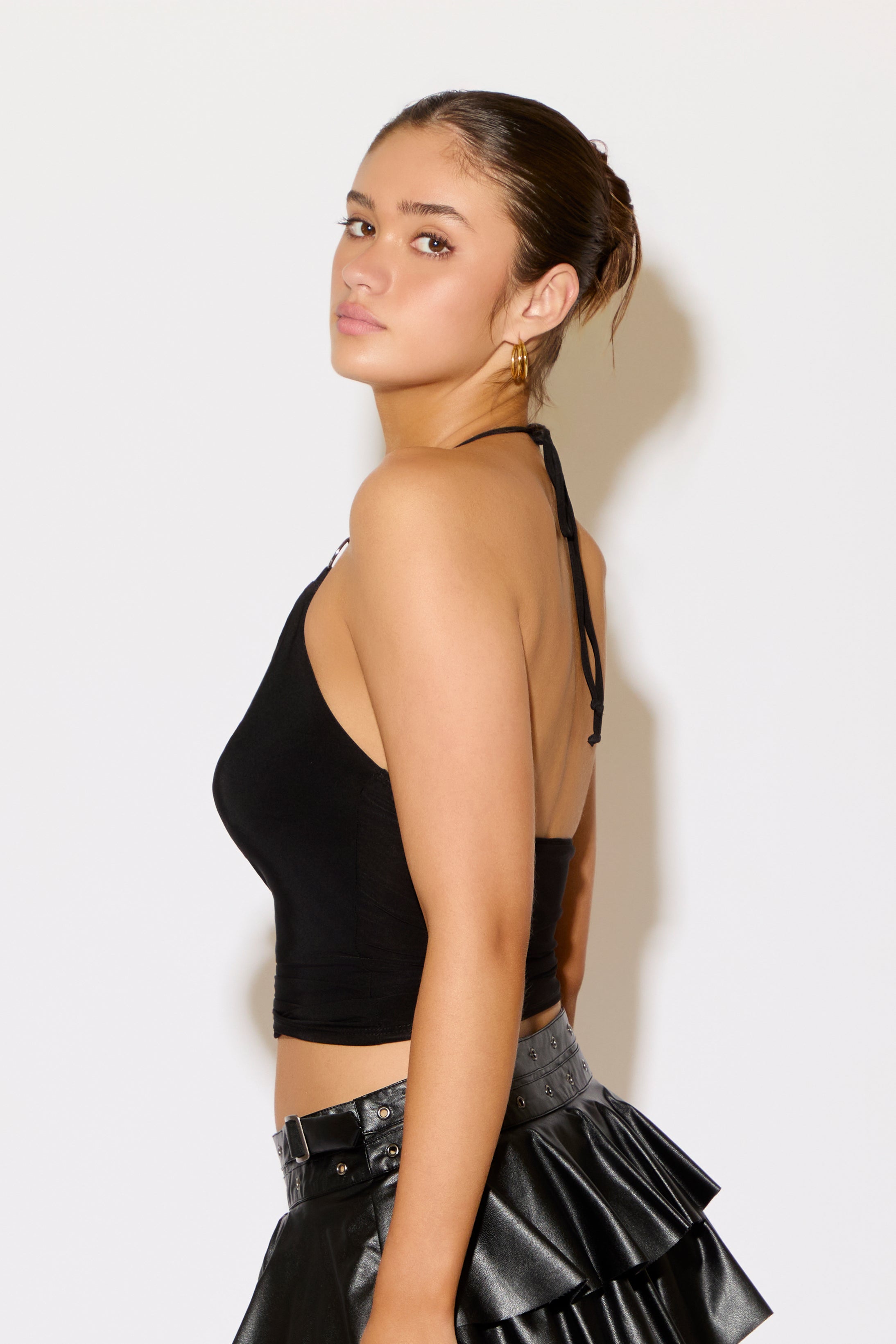 Woman wearing a black crop top and black skirt against a white background